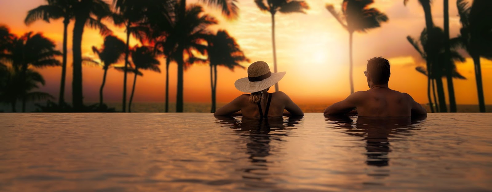 Couple enjoying a romantic getaway in a swimming pool at sunset, surrounded by vibrant colors and serene atmosphere.
